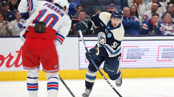 Mar 15, 2025; Columbus, Ohio, USA;  Columbus Blue Jackets right wing Yegor Chinakhov (59) shoots the puck as New York Rangers left wing Artemi Panarin (10) defends during the second period at Nationwide Arena. Mandatory Credit: Joseph Maiorana-Imagn Images