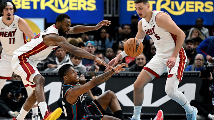 Jan 1, 2026; Detroit, Michigan, USA; Detroit Pistons guard Marcus Sasser (25) passes the ball from the floor after getting to a loose ball ahead of Miami Heat forwards Andrew Wiggins (22) and Nikola Jovic (5) in the fourth quarter at Little Caesars Arena. Mandatory Credit: Lon Horwedel-Imagn Images