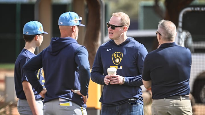 Matt Arnold, Milwaukee Brewers president of baseball operations and general manager, third from left, talks with his son Tyler, Milwaukee Brewers third base coach Matt Erickson team physician Dr. Mark Niedfeldt during spring training workouts Sunday, February 15, 2026, at American Family Fields of Phoenix in Phoenix, Arizona.