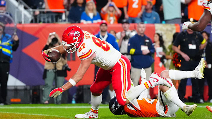 Nov 16, 2025; Denver, Colorado, USA; Kansas City Chiefs tight end Travis Kelce (87) scores a touchdown past Denver Broncos cornerback Riley Moss (21) in the fourth quarter at Empower Field at Mile High. Mandatory Credit: Ron Chenoy-Imagn Images