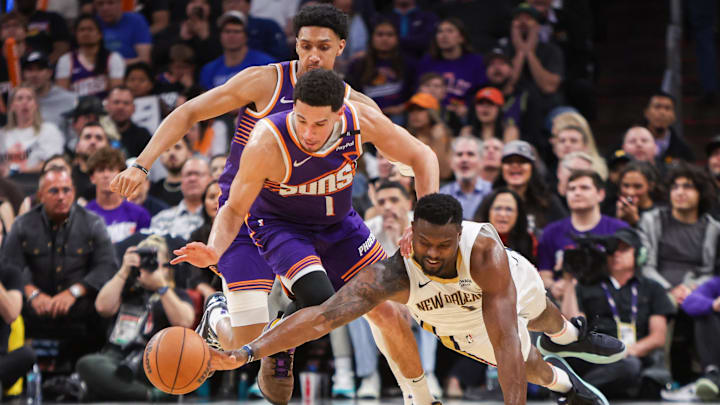 Feb 27, 2025; Phoenix, Arizona, USA; New Orleans Pelicans forward Zion Williamson (1) dives for a loose ball in front of Phoenix Suns guard Devin Booker (1) in the fourth quarter at Footprint Center. Mandatory Credit: Brett Davis-Imagn Images