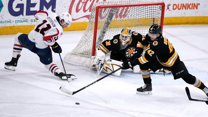 Providence Bruins goalie Michael DiPietro and defender Frederic Brunet deflect the puck from Thunderbird Dylan Peterson away from the Providence goal.