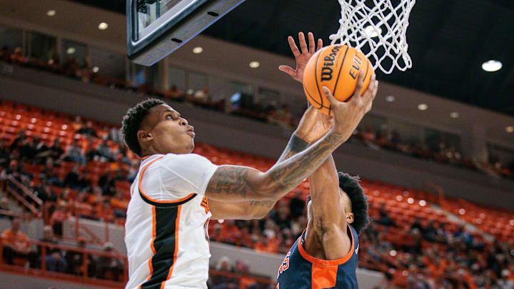 Dec 21, 2025; Stillwater, Oklahoma, USA; Oklahoma State Cowboys guard Christian Coleman (4) shoots the ball around Cal State Fullerton Titans guard Christian Williams (7) during the first half at Gallagher-Iba Arena. Mandatory Credit: William Purnell-Imagn Images