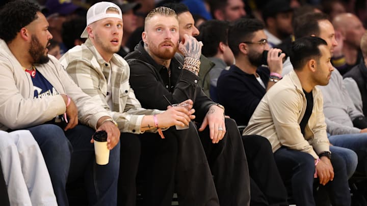 Mar 22, 2024; Los Angeles, California, USA;  An NFL player Maxx Crosby (C) attends the game between the Philadelphia 76ers and the Los Angeles Lakers at Crypto.com Arena. Mandatory Credit: Kiyoshi Mio-Imagn Images