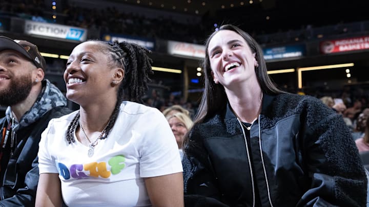 Oct 14, 2024; Indianapolis, Indiana, USA; Indiana Fever guard Caitlin Clark (22) and guard Kelsey Mitchell (0) take in the game between the Indiana Pacers and the Memphis Grizzlies at Gainbridge Fieldhouse. Mandatory Credit: Trevor Ruszkowski-Imagn Images