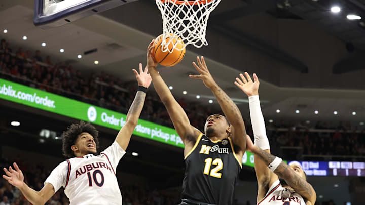 Jan 4, 2025; Auburn, Alabama, USA; Missouri Tigers guard Tony Perkins (12) takes a shot between Auburn Tigers guard Chad Baker-Mazara (10) and forward Johni Broome (4) during the first half at Auburn Arena. Mandatory Credit: John Reed-Imagn Images Jan 4, 2025; Auburn, Alabama, USA; Missouri Tigers guard Tony Perkins (12) takes a shot between Auburn Tigers guard Chad Baker-Mazara (10) and forward Johni Broome (4) during the first half at Auburn Arena. Mandatory Credit: John Reed-Imagn Images