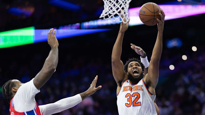 Nov 12, 2024; Philadelphia, Pennsylvania, USA; New York Knicks center Karl-Anthony Towns (32) drives for a shot next to Philadelphia 76ers center Andre Drummond (5) during the second quarter at Wells Fargo Center. Mandatory Credit: Bill Streicher-Imagn Images