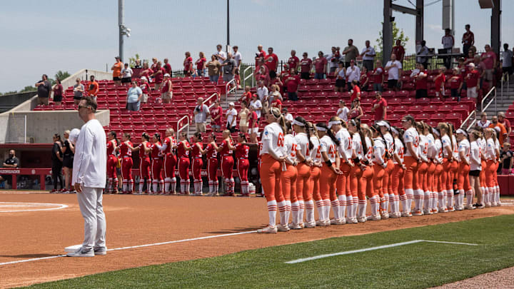 May 16, 2025; Fayetteville, AR, USA;  Oklahoma State Cowgirls head coach Kenny Gajewski and players from Oklahoma State Cowgirls and the Indiana Hoosiers stand for the National Anthem before their game.  Oklahoma State won 11-6.  Mandatory Credit: Brett Rojo-Imagn Images