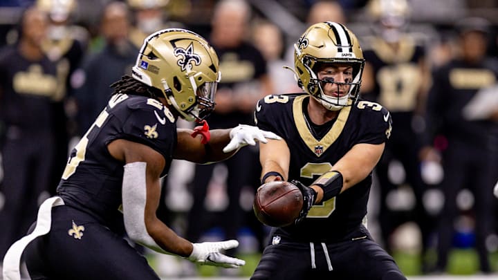 Dec 15, 2024; New Orleans, Louisiana, USA;  New Orleans Saints quarterback Jake Haener (3) hands off to running back Kendre Miller (25) against the Washington Commanders during the first half at Caesars Superdome. Mandatory Credit: Stephen Lew-Imagn Images