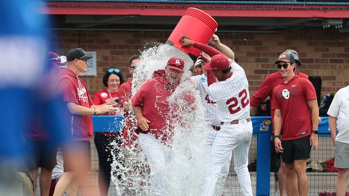 Oklahoma Sooners coach Skip Johnson gets a water bath after defeating Kansas Jayhawks 13-2 during the NCAA Lawrence Super Regional game at Hoglund Ballpark on June 8, 2026. Oklahoma Sooners coach Skip Johnson gets a water bath after defeating Kansas Jayhawks 13-2 during the NCAA Lawrence Super Regional game at Hoglund Ballpark on June 8, 2026.
