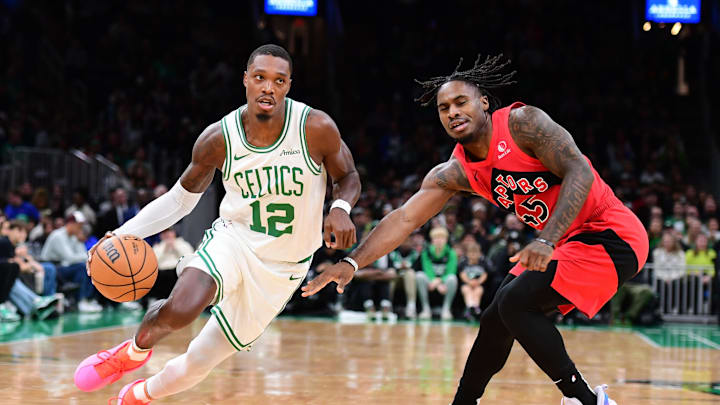 Oct 13, 2024; Boston, Massachusetts, USA;  Boston Celtics guard Lonnie Walker IV (12) controls the ball while Toronto Raptors guard Davion Mitchell (45) defends during the first half at TD Garden. Mandatory Credit: Bob DeChiara-Imagn Images