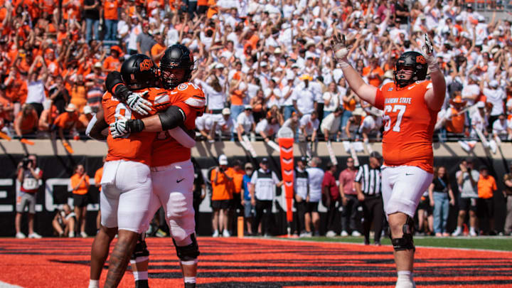 Sep 7, 2024; Stillwater, Oklahoma, USA; Oklahoma State Cowboys offensive lineman Cole Birmingham (67) Oklahoma State Cowboys offensive lineman Preston Wilson (74) and Oklahoma State Cowboys running back Ollie Gordon II (0) celebrate after a touchdown during the second overtime against the Arkansas Razorbacks at Boone Pickens Stadium. Mandatory Credit: William Purnell-Imagn Images Sep 7, 2024; Stillwater, Oklahoma, USA; Oklahoma State Cowboys offensive lineman Cole Birmingham (67) Oklahoma State Cowboys offensive lineman Preston Wilson (74) and Oklahoma State Cowboys running back Ollie Gordon II (0) celebrate after a touchdown during the second overtime against the Arkansas Razorbacks at Boone Pickens Stadium. Mandatory Credit: William Purnell-Imagn Images