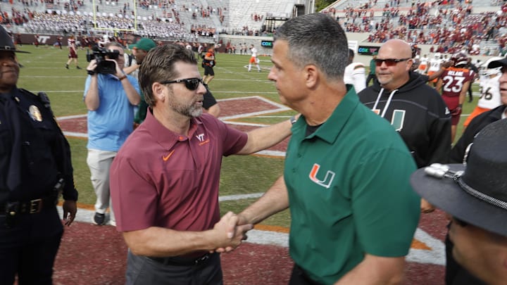 Oct 15, 2022; Blacksburg, Virginia, USA;  Virginia Tech Hokies head coach Brent Pry (left) and Miami Hurricanes head coach Mario Cristobal shake hands near mid field after the game at Lane Stadium. Mandatory Credit: Reinhold Matay-Imagn Images