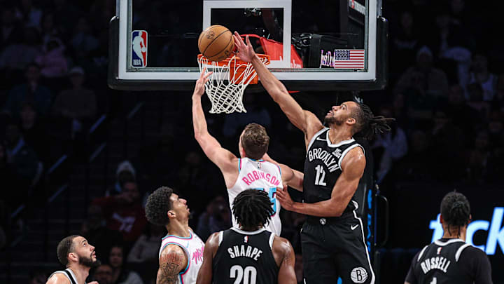 Feb 7, 2025; Brooklyn, New York, USA; Brooklyn Nets forward Tosan Evbuomwan (12) blocks a shot by Miami Heat forward Duncan Robinson (55) during the first half at Barclays Center. Mandatory Credit: Vincent Carchietta-Imagn Images