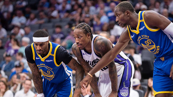 Oct 9, 2024; Sacramento, California, USA; Golden State Warriors guard Gary Payton II (0) and forward Jonathan Kuminga (00) defend against Sacramento Kings forward DeMar DeRozan (10) during a free throw attempt in the second quarter at Golden 1 Center. Mandatory Credit: Ed Szczepanski-Imagn Images