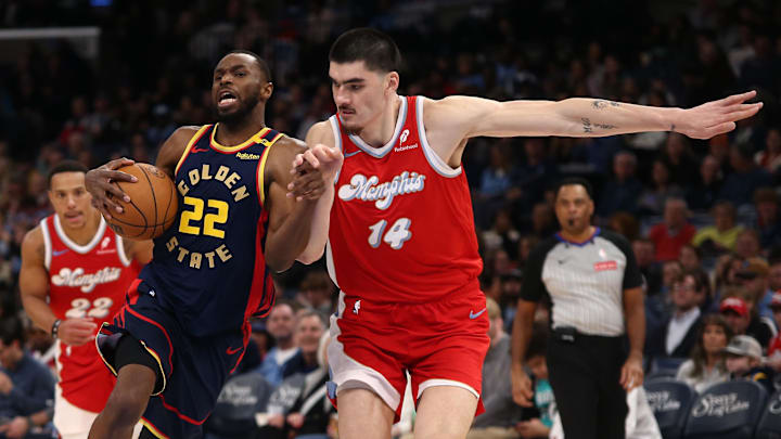 Dec 19, 2024; Memphis, Tennessee, USA; Golden State Warriors forward Andrew Wiggins (22) drives to the basket as Memphis Grizzlies center Zach Edey (14) defends during the third quarter at FedExForum. Mandatory Credit: Petre Thomas-Imagn Images