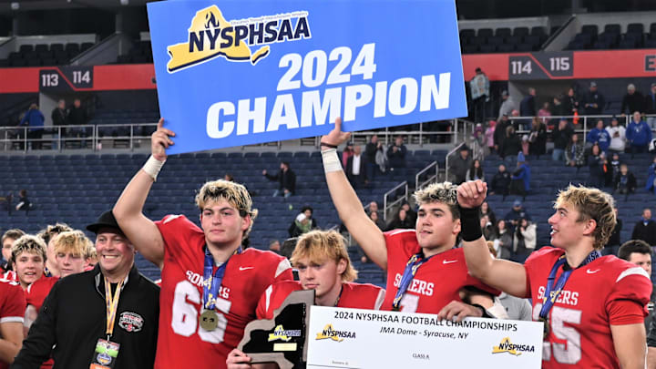 Somers players hold their plaque and signs after beating Whitesboro in the NYSPHSAA Class A football championship game for the second year in a row Friday, Dec. 6, 2024, at the JMA Wireless Dome in Syracuse, New York.
