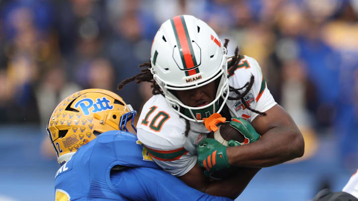 Nov 29, 2025; Pittsburgh, Pennsylvania, USA;  Miami Hurricanes wide receiver Malachi Toney (10) runs after a catch as Pittsburgh Panthers defensive end Isaiah Neal (2) tackles during the first quarter at Acrisure Stadium. Mandatory Credit: Charles LeClaire-Imagn Images