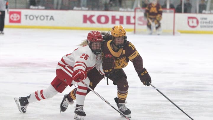 Wisconsin's Casey O'Brien (26) knocks the puck away from Minnesota's Abbey Murphy on Saturday February 17, 2024 at La Bahn Arena in Madison, Wisconsin.
