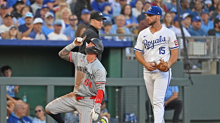 Sep 7, 2024; Kansas City, Missouri, USA; Minnesota Twins designated hitter Jose Miranda (64) reacts after hitting a RBI triple in the third inning as Kansas City Royals third baseman Paul DeJong (15) looks on at Kauffman Stadium. Mandatory Credit: Peter Aiken-Imagn Images