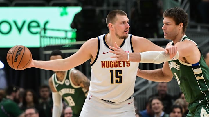 Feb 27, 2025; Milwaukee, Wisconsin, USA; Denver Nuggets center Nikola Jokic (15) looks to pass the ball against Milwaukee Bucks center Brook Lopez (11) in the first quarter at Fiserv Forum. Mandatory Credit: Benny Sieu-Imagn Images