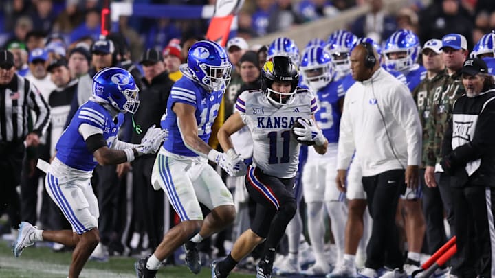 Nov 16, 2024; Provo, Utah, USA; Kansas Jayhawks wide receiver Luke Grimm (11) runs for a first down against Brigham Young Cougars cornerback Jakob Robinson (0) and linebacker Isaiah Glasker (16) during the third quarter at LaVell Edwards Stadium. 