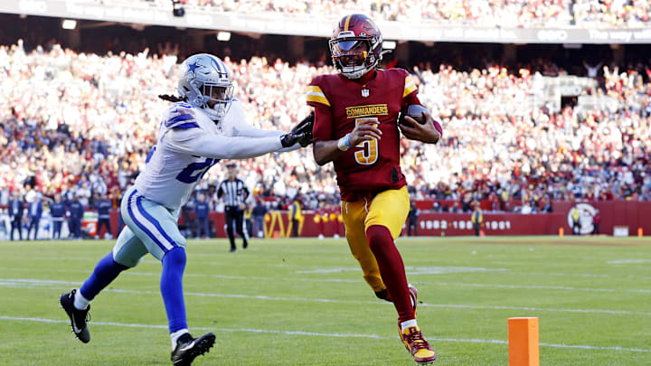 Nov 24, 2024; Landover, Maryland, USA; Washington Commanders quarterback Jayden Daniels (5) runs for a touchdown against Dallas Cowboys safety Malik Hooker (28) during the third quarter at Northwest Stadium. Mandatory Credit: Peter Casey-Imagn Images