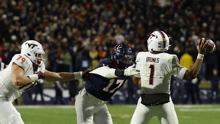 Nov 29, 2025; Charlottesville, Va.; Virginia Tech quarterback Kyron Drones (1) passes the ball under pressure from Virginia defensive end Mitchell Melton (17).