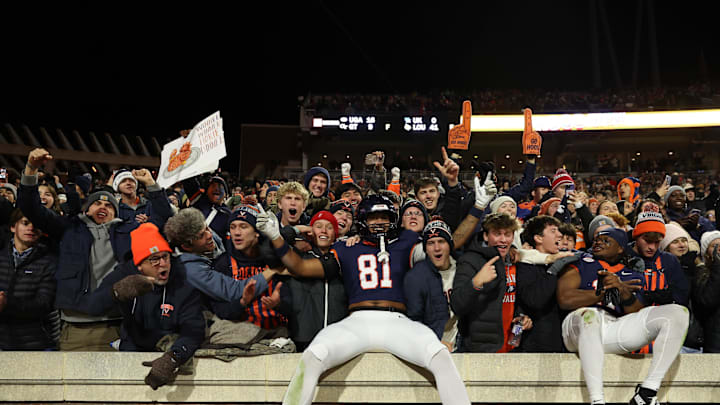 Nov 29, 2025; Charlottesville, Virginia, USA; Virginia Cavaliers tight end Tekai Kirby (81) and Cavaliers wide receiver Trell Harris (11) leap onto the wall in the student sections to celebrate with students and fans after their game against the Virginia Tech Hokies at Scott Stadium. Mandatory Credit: Geoff Burke-Imagn Images