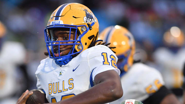Miami Northwestern quarterback Leon Strawder (#12) is brought down by Venice High defensive end Asharri Charles (#5) on a quarterback keeper earlier this season. Strawder threw four TD passes and ran for another score to lead the Bulls past Jacksonville Raines, 41-0, for the state title on Dec. 14.