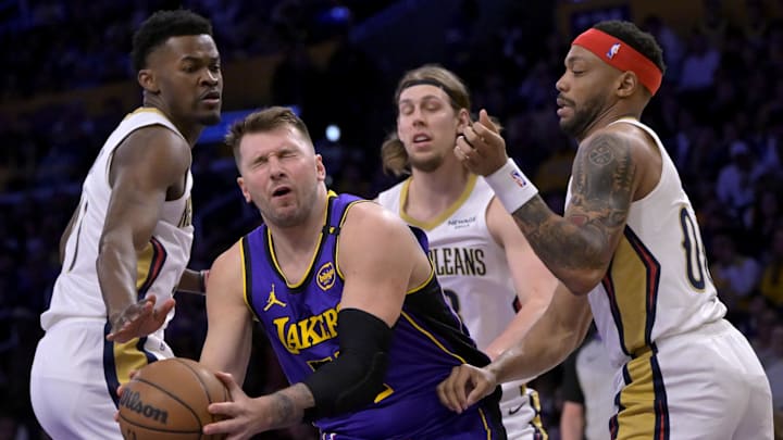 Apr 4, 2025; Los Angeles, California, USA;  Los Angeles Lakers guard Luka Doncic (77) reacts after he was hit in the face driving past New Orleans Pelicans center Yves Missi (21) and forward Bruce Brown (00) in the first half at Crypto.com Arena. Mandatory Credit: Jayne Kamin-Oncea-Imagn Images