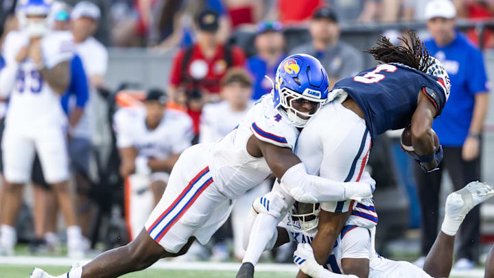 Nov 8, 2025; Tucson, Arizona, USA; Kansas Jayhawks linebacker Trey Lathan (4) tackles Arizona Wildcats wide receiver Javin Whatley (6) at Arizona Stadium. Mandatory Credit: Mark J. Rebilas-Imagn Images