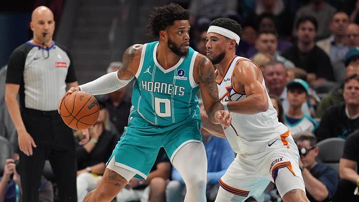 Apr 2, 2026; Charlotte, North Carolina, USA; Charlotte Hornets forward Miles Bridges (0) works the ball against Phoenix Suns guard Devin Booker (1)during the first quarter at Spectrum Center. Mandatory Credit: Jim Dedmon-Imagn Images