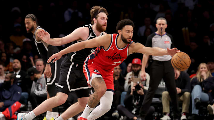 Mar 28, 2025; Brooklyn, New York, USA; Los Angeles Clippers guard Ben Simmons (25) reaches for a pass in front of Brooklyn Nets forward Drew Timme (26) during the fourth quarter at Barclays Center. Mandatory Credit: Brad Penner-Imagn Images
