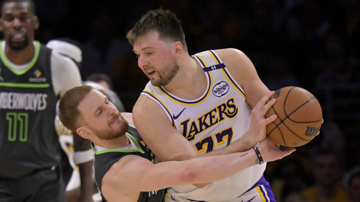 Apr 19, 2025; Los Angeles, California, USA; Minnesota Timberwolves guard Donte DiVincenzo (0) reaches in on Los Angeles Lakers guard Luka Doncic (77) in the second half at Crypto.com Arena. Mandatory Credit: Jayne Kamin-Oncea-Imagn Images