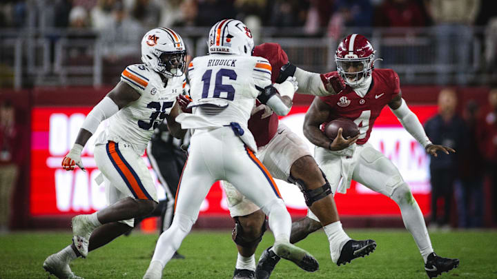 Nov 30, 2024; Tuscaloosa, Alabama, USA; Alabama Crimson Tide quarterback Jalen Milroe (4) runs the ball against Auburn Tigers nose tackle Jalen McLeod (35) and linebacker Demarcus Riddick (16) during the fourth quarter at Bryant-Denny Stadium. Mandatory Credit: Will McLelland-Imagn Images
