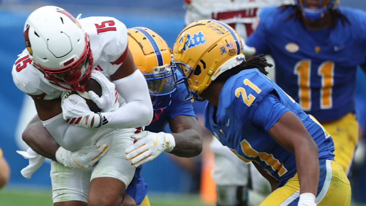 Sep 27, 2025; Pittsburgh, Pennsylvania, USA;  Louisville Cardinals wide receiver Antonio Meeks (15) is tackled after a catch by Pittsburgh Panthers linebacker Rasheem Biles (3) and defensive back Shadarian Harrison (21) during the third quarter at Acrisure Stadium. Mandatory Credit: Charles LeClaire-Imagn Images
