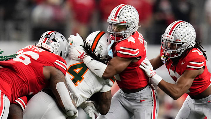 Ohio State Buckeyes defensive back Caleb Downs (2) and defensive end Eddrick Houston (96) tackle Miami Hurricanes running back Mark Fletcher Jr. (4) during the Cotton Bowl at AT&T Stadium in Arlington, Texas for the College Football Playoff quarterfinal game on Dec. 31, 2025. Ohio State lost 24-14.