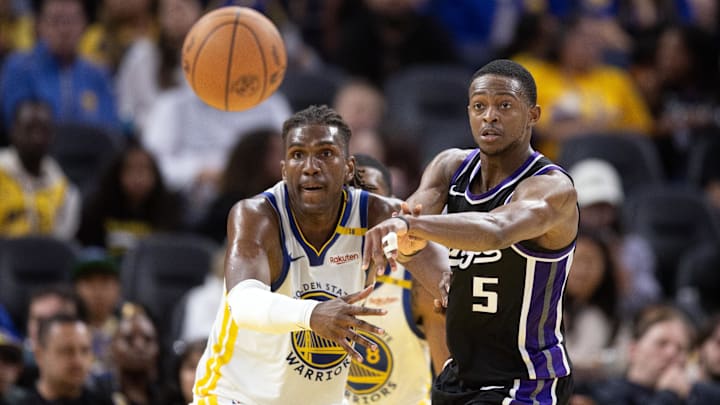 Oct 11, 2024; San Francisco, California, USA; Sacramento Kings guard De'Aaron Fox (5) passes away from defensive pressure by Golden State Warriors forward Kevon Looney (5) during the third quarter at Chase Center. Mandatory Credit: D. Ross Cameron-Imagn Images