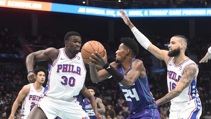 Dec 3, 2024; Charlotte, North Carolina, USA;  Charlotte Hornets forward Brandon Miller (24) looks to shoot through the defense of Philadelphia 76ers center Adam Bona (30) and forward Caleb Martin (11) during the second half at the Spectrum Center. Mandatory Credit: Sam Sharpe-Imagn Images