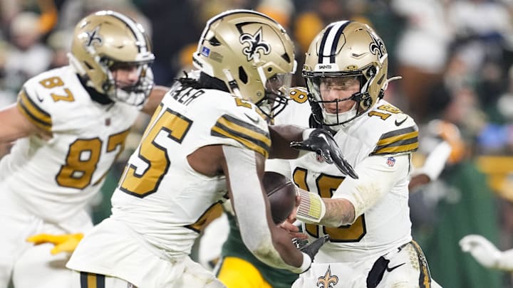 Dec 23, 2024; Green Bay, Wisconsin, USA;  New Orleans Saints quarterback Spencer Rattler (18) hands the football off to running back Kendre Miller (25) during the third quarter against the Green Bay Packers at Lambeau Field. Mandatory Credit: Jeff Hanisch-Imagn Images
