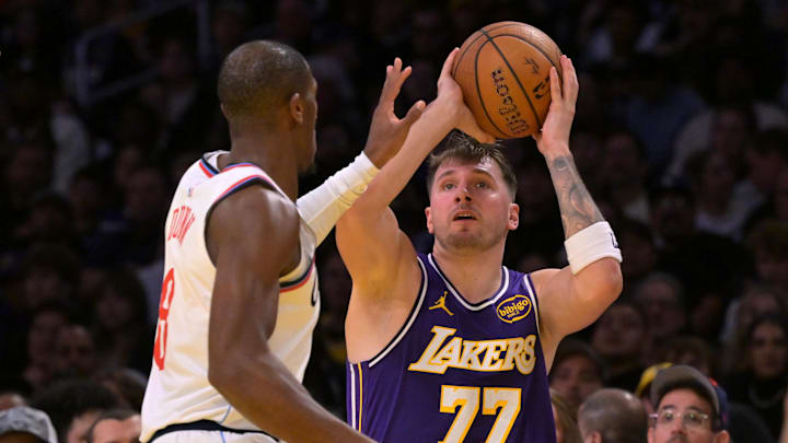 Nov 25, 2025; Los Angeles, California, USA;  Los Angeles Lakers guard Luka Doncic (77) is defended by Los Angeles Clippers guard Kris Dunn (8) during the first half at Crypto.com Arena. Mandatory Credit: Jayne Kamin-Oncea-Imagn Images