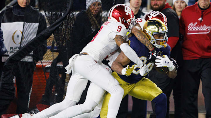 Notre Dame running back Jadarian Price (24) is brought down by Indiana defensive back Jamier Johnson (9) and defensive back Terry Jones Jr. (12) during the first round of the College Football Playoff between Notre Dame and Indiana at Notre Dame Stadium on Friday, Dec. 20, 2024, in South Bend.