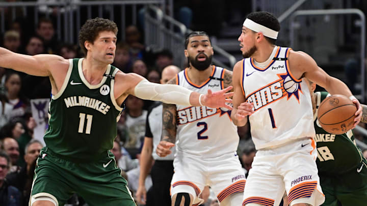 Apr 1, 2025; Milwaukee, Wisconsin, USA;  Phoenix Suns guard Devin Booker (1) looks for a shot against Milwaukee Bucks center Brook Lopez (11) in the fourth quarter at Fiserv Forum. Mandatory Credit: Benny Sieu-Imagn Images