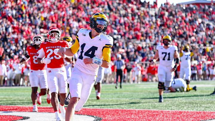 Oct 31, 2026; Piscataway, New Jersey, USA; Michigan Wolverines quarterback Tommy Carr (14) scores on a rushing touchdown during the second half in front of Rutgers Scarlet Knights defensive lineman RJ Johnson Jr. (14) at SHI Stadium. Mandatory Credit: Vincent Carchietta-Imagn Images Oct 31, 2026; Piscataway, New Jersey, USA; Michigan Wolverines quarterback Tommy Carr (14) scores on a rushing touchdown during the second half in front of Rutgers Scarlet Knights defensive lineman RJ Johnson Jr. (14) at SHI Stadium. Mandatory Credit: Vincent Carchietta-Imagn Images