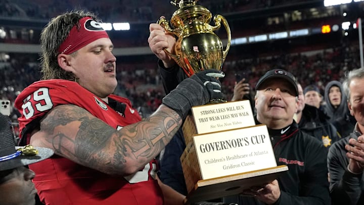 Georgia coach Kirby Smart hands the governor cup to Georgia offensive lineman Tate Ratledge (69) after Georgia won a NCAA college football game against Georgia Tech in overtime in Athens, Ga., on Friday, Nov. 29, 2024. Georgia won 44-42.