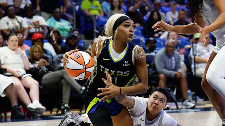 Dallas Wings guard DiJonai Carrington looks to pass against Las Vegas Aces forward Kierstan Bell.
