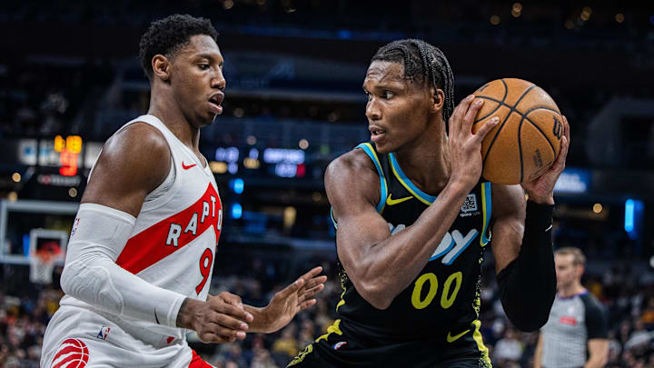 Feb 26, 2024; Indianapolis, Indiana, USA; Indiana Pacers guard Bennedict Mathurin (00) holds the ball while Toronto Raptors guard RJ Barrett (9) defends in the second half at Gainbridge Fieldhouse. Mandatory Credit: Trevor Ruszkowski-Imagn Images