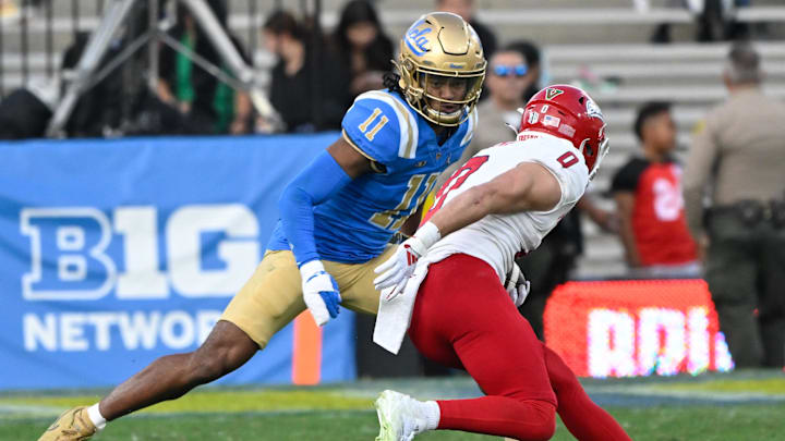 Nov 30, 2024; Pasadena, California, USA; UCLA Bruins defensive back Ramon Henderson (11) moves in to tackle Fresno State Bulldogs wide receiver Mac Dalena (0) during the fourth quarter at Rose Bowl. Mandatory Credit: Robert Hanashiro-Imagn Images