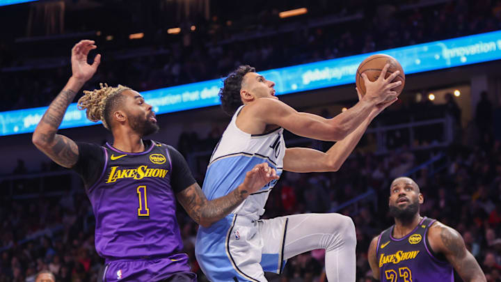 Dec 6, 2024; Atlanta, Georgia, USA; Atlanta Hawks forward Zaccharie Risacher (10) shoots past Los Angeles Lakers guard D'Angelo Russell (1) and forward LeBron James (23) in the fourth quarter at State Farm Arena. Mandatory Credit: Brett Davis-Imagn Images

